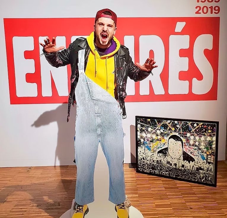 Zoulli Art devant le logo des Enfoirés